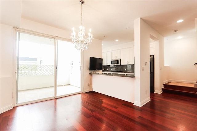 1020 Hilldale Ave, West Hollywood, CA 90069 - kitchen featuring dark wood finished floors, stainless steel microwave, backsplash, and a notable chandelier