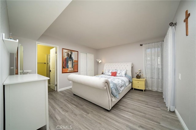 bedroom with baseboards, a closet, light wood-type flooring, and connected bathroom