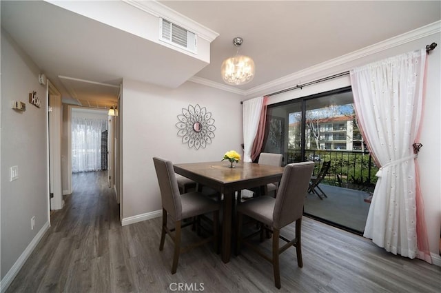 dining area with visible vents, ornamental molding, wood finished floors, baseboards, and a chandelier