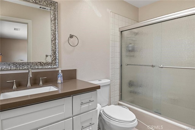 full bath featuring bath / shower combo with glass door, toilet, visible vents, and vanity
