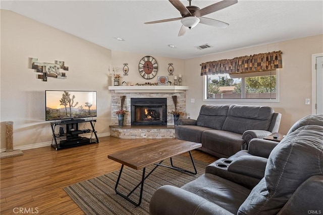 living room featuring a fireplace, wood finished floors, a ceiling fan, and visible vents