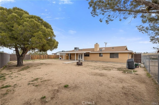 back of property with a chimney, a patio area, stucco siding, french doors, and a fenced backyard