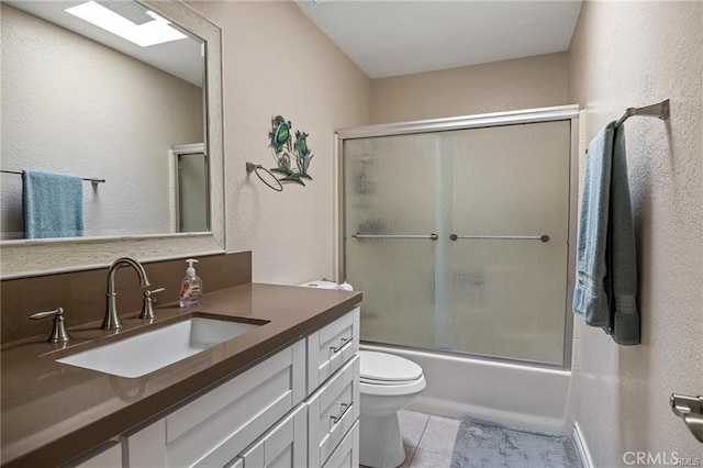 bathroom featuring bath / shower combo with glass door, a textured wall, toilet, vanity, and tile patterned flooring