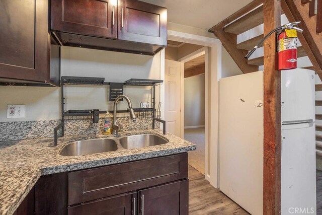 550 Pine Ln, Sugarloaf, CA 92386 - kitchen with dark brown cabinetry, freestanding refrigerator, light stone counters, a sink, and light wood-type flooring