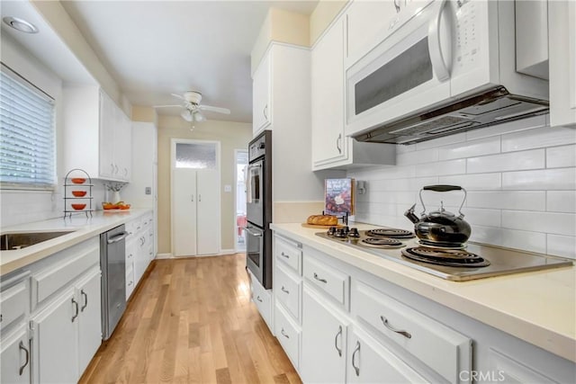 927 Alta Loma Dr, Corona, CA 92882 - kitchen with stainless steel appliances, a ceiling fan, backsplash, white cabinetry, and light wood-style floors