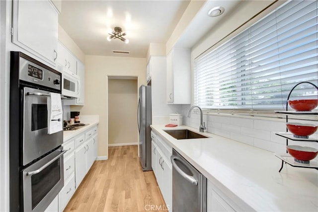 927 Alta Loma Dr, Corona, CA 92882 - kitchen with appliances with stainless steel finishes, light countertops, white cabinets, and light wood finished floors