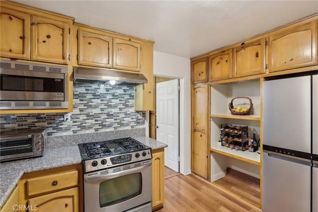 4447 Walnut Ave, Chino, CA 91710 - kitchen featuring decorative backsplash, light wood-style flooring, stainless steel appliances, under cabinet range hood, and a toaster