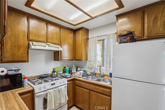 4447 Walnut Ave, Chino, CA 91710 - kitchen featuring white appliances, under cabinet range hood, light countertops, brown cabinets, and a sink