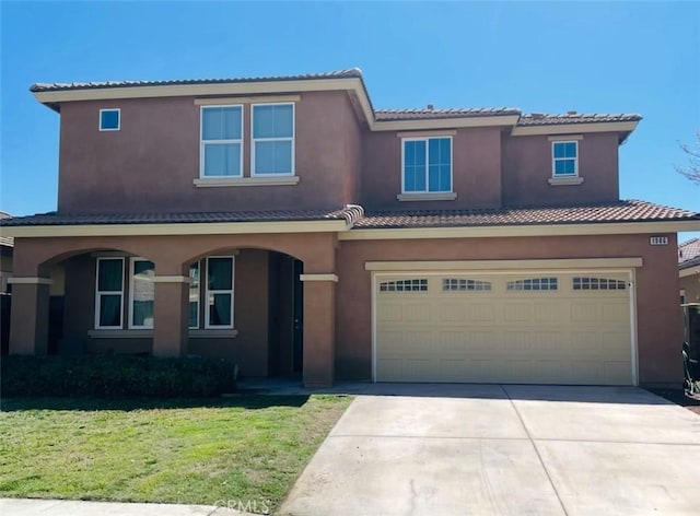 view of front facade featuring a garage, driveway, a front yard, stucco siding, and a tiled roof