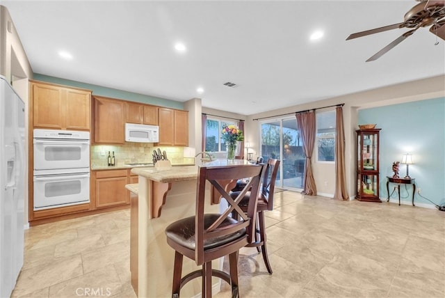 19069 Eldorado Rd, Perris, CA 92570 - kitchen with white appliances, light countertops, tasteful backsplash, a breakfast bar area, and ceiling fan