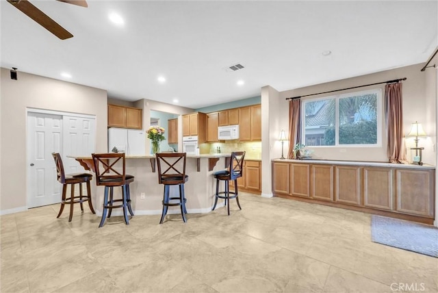 19069 Eldorado Rd, Perris, CA 92570 - kitchen with white appliances, light countertops, a kitchen breakfast bar, recessed lighting, and a ceiling fan