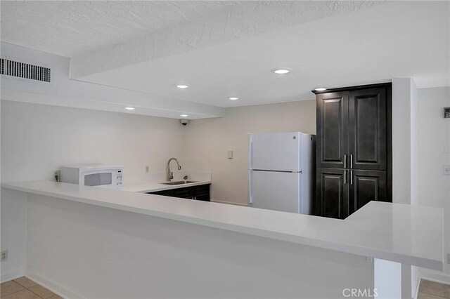 21650 Burbank Blvd Unit 111, Woodland Hills, CA 91367 - kitchen with white appliances, light tile patterned floors, light countertops, a sink, and visible vents