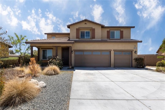 mediterranean / spanish-style home featuring a garage, fence, stucco siding, a tiled roof, and concrete driveway