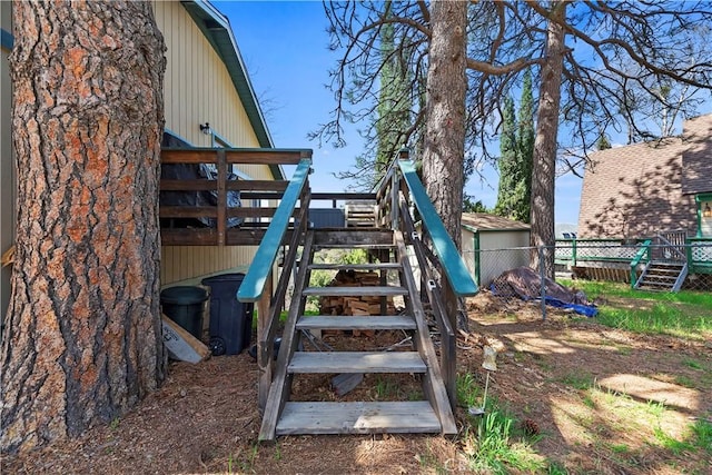 view of play area featuring fence, stairway, and a deck