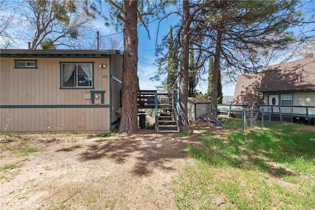 view of property exterior featuring fence, stairs, and an outbuilding
