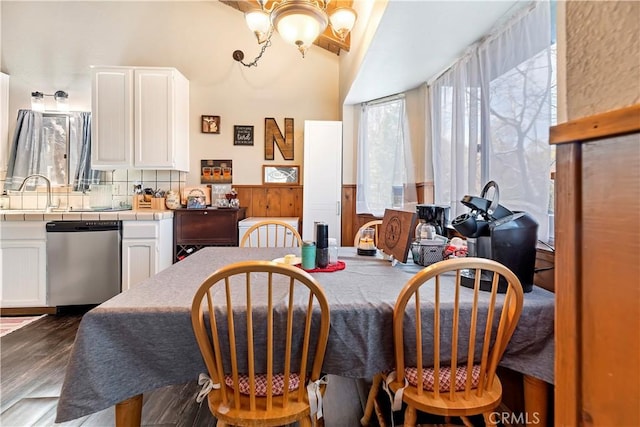 dining room featuring a wainscoted wall, a notable chandelier, and dark wood-style flooring