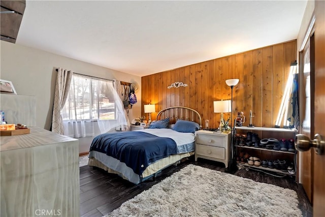 bedroom with wooden walls and dark wood-style floors