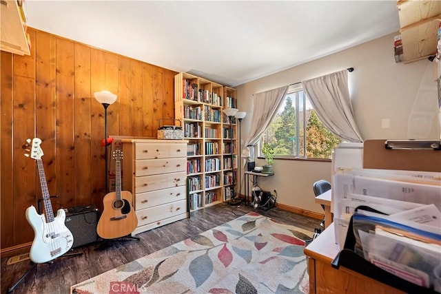 bedroom featuring wood walls, wood finished floors, and baseboards
