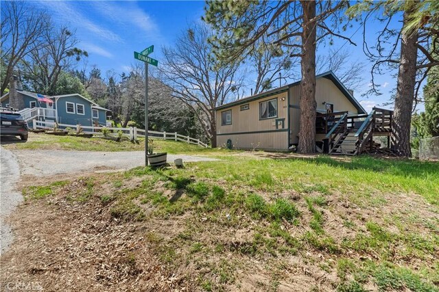 view of yard featuring a deck, fence, and stairs