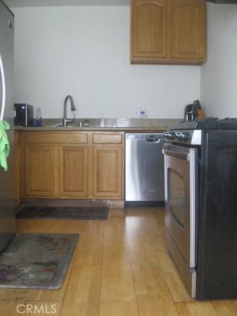 2927 S Genesee Ave, Los Angeles, CA 90016 - kitchen with brown cabinetry, a sink, stainless steel appliances, and light wood-type flooring