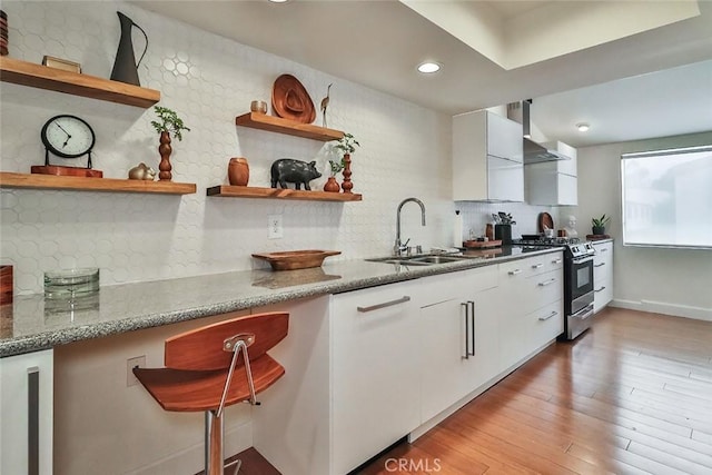 21025 Lemarsh St Unit G39, Chatsworth, CA 91311 - kitchen featuring stainless steel gas range, open shelves, a sink, wall chimney exhaust hood, and white cabinets