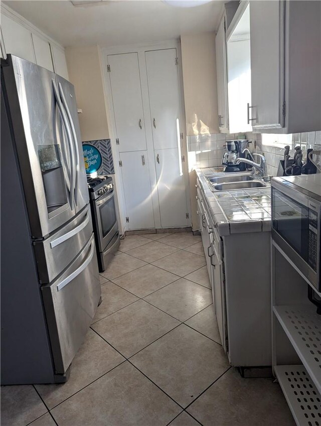 33111 Baldwin Blvd, Lake Elsinore, CA 92530 - kitchen featuring white cabinets, appliances with stainless steel finishes, a sink, tile counters, and tasteful backsplash