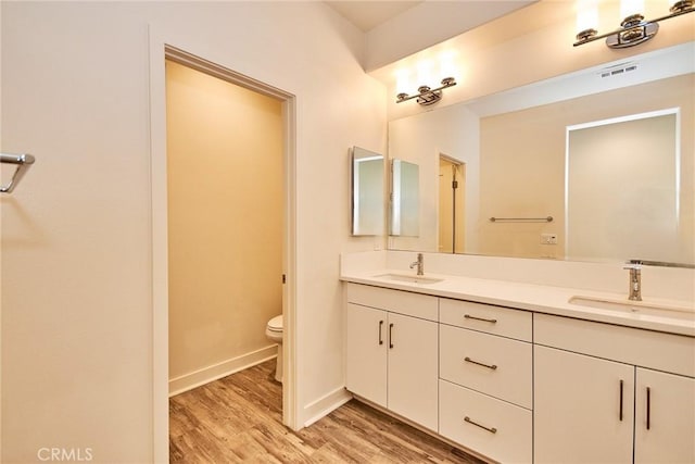full bathroom with wood finished floors, toilet, visible vents, and a sink