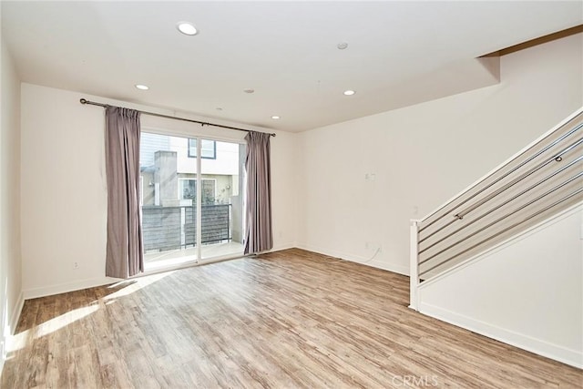 unfurnished living room featuring light wood-type flooring, baseboards, recessed lighting, and stairs