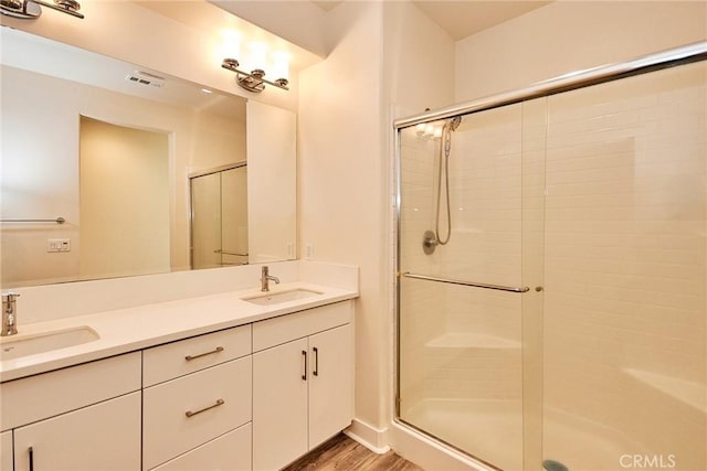 full bathroom featuring wood finished floors, visible vents, a shower stall, and a sink