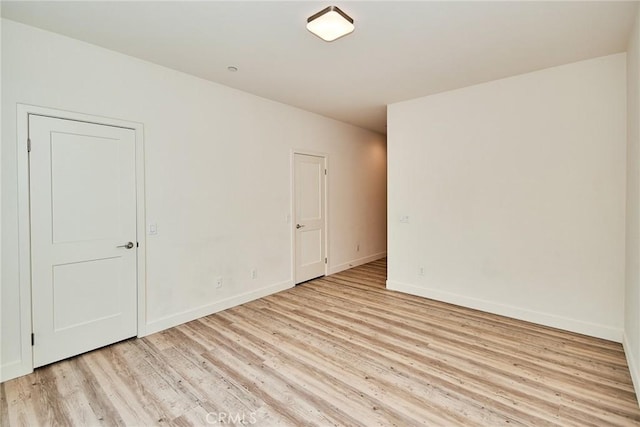 unfurnished room with light wood-type flooring and baseboards
