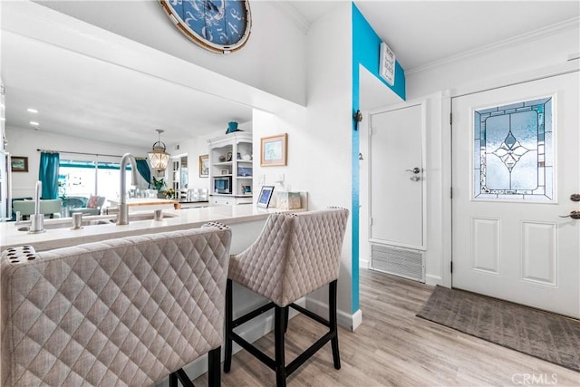 entrance foyer featuring wood finished floors, an inviting chandelier, baseboards, visible vents, and crown molding