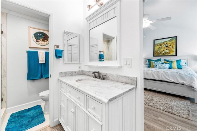 bathroom with wood finished floors, ceiling fan, toilet, ensuite bathroom, and vanity