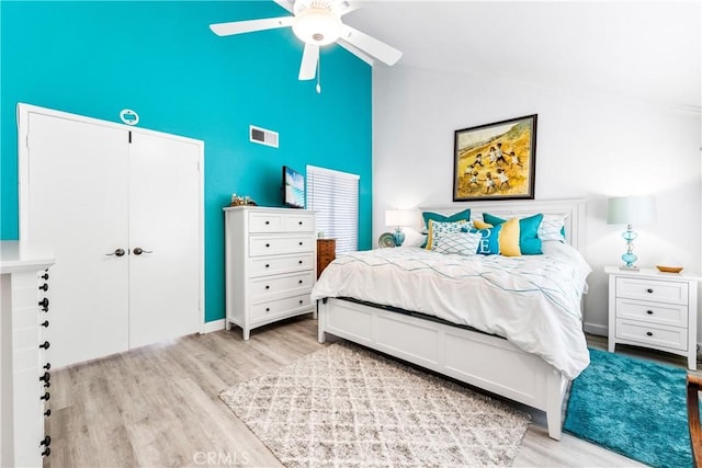 bedroom with a closet, high vaulted ceiling, ceiling fan, visible vents, and wood finished floors