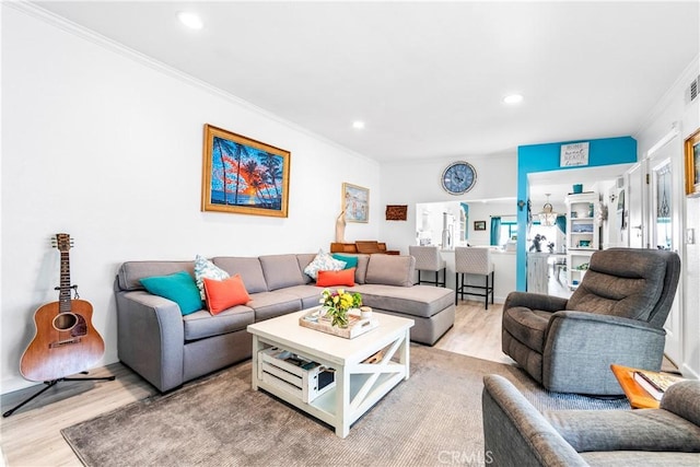 living area with wood finished floors, plenty of natural light, crown molding, and recessed lighting