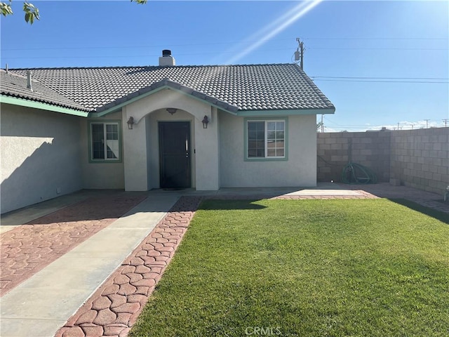 8740 S Loop Blvd, California City, CA 93505 - ranch-style house featuring stucco siding, a tile roof, fence, and a front yard
