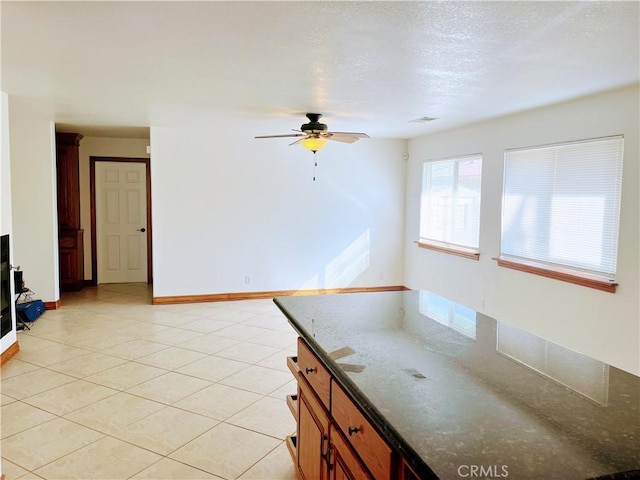 8740 S Loop Blvd, California City, CA 93505 - kitchen featuring a ceiling fan, baseboards, light tile patterned floors, dark stone countertops, and brown cabinets