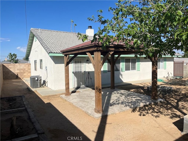 8740 S Loop Blvd, California City, CA 93505 - rear view of property featuring a tiled roof, stucco siding, a chimney, and fence