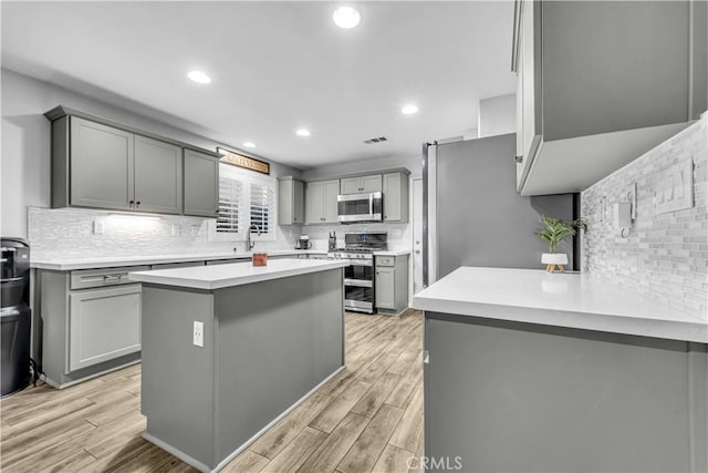 kitchen with tasteful backsplash, gray cabinets, and stainless steel appliances