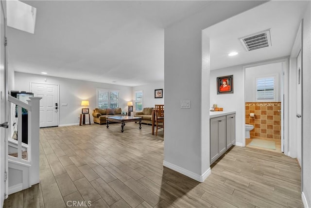hall with recessed lighting, visible vents, wood finished floors, and baseboards