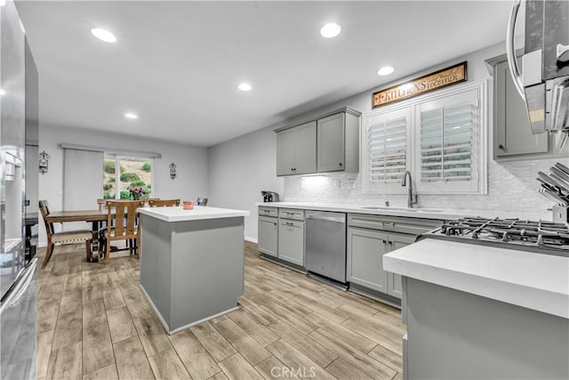 kitchen featuring a sink, a center island, dishwasher, and gray cabinets