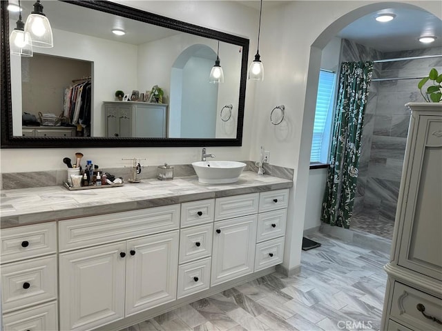 full bath featuring walk in shower, double vanity, a sink, and a spacious closet
