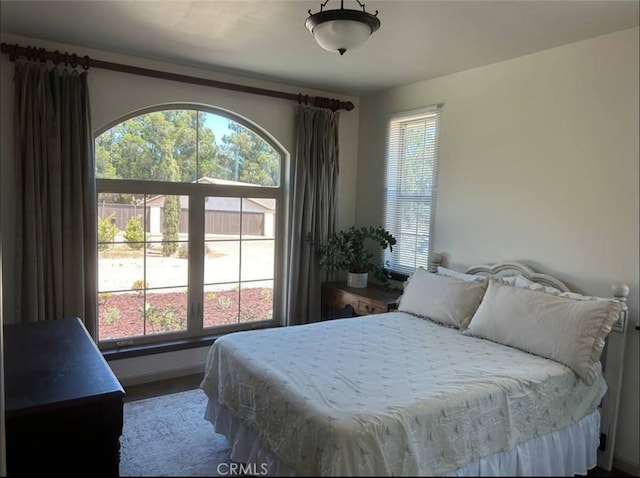 bedroom featuring wood finished floors, baseboards, and multiple windows