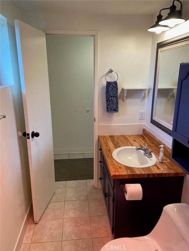 bathroom featuring tile patterned floors, vanity, toilet, and baseboards