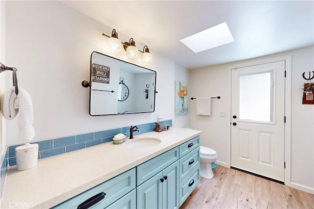 1160 Easy Ln, Nipomo, CA 93444 - bathroom featuring a skylight, vanity, toilet, wood finished floors, and decorative backsplash