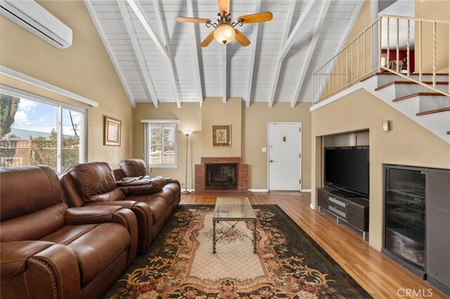 650 N Acacia, Rialto, CA 92376 - living room with an AC wall unit, wood finished floors, a ceiling fan, beam ceiling, and a brick fireplace