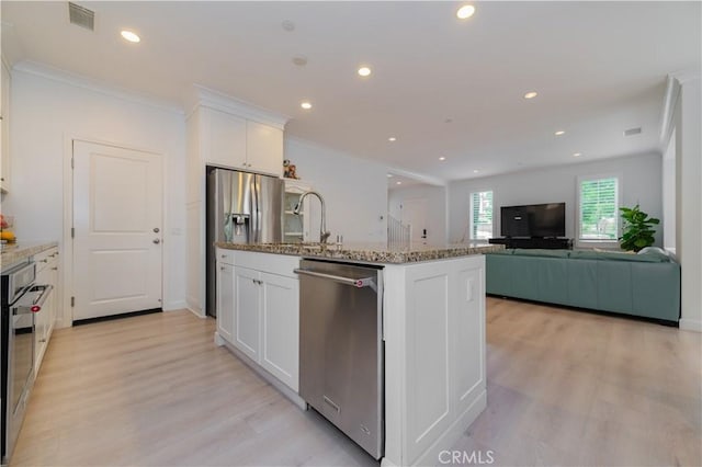 kitchen featuring visible vents, light stone countertops, a sink, light wood finished floors, and appliances with stainless steel finishes