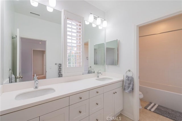 bathroom with double vanity, toilet, visible vents, and a sink