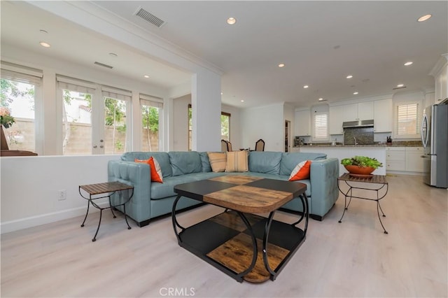 living area featuring crown molding, recessed lighting, visible vents, and light wood finished floors