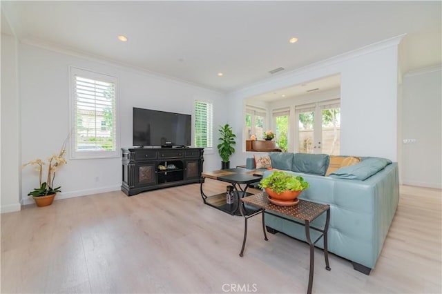 living area featuring plenty of natural light, ornamental molding, and light wood-style flooring