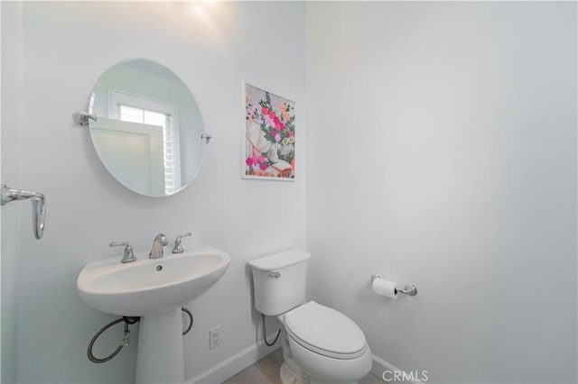 half bath featuring toilet and baseboards